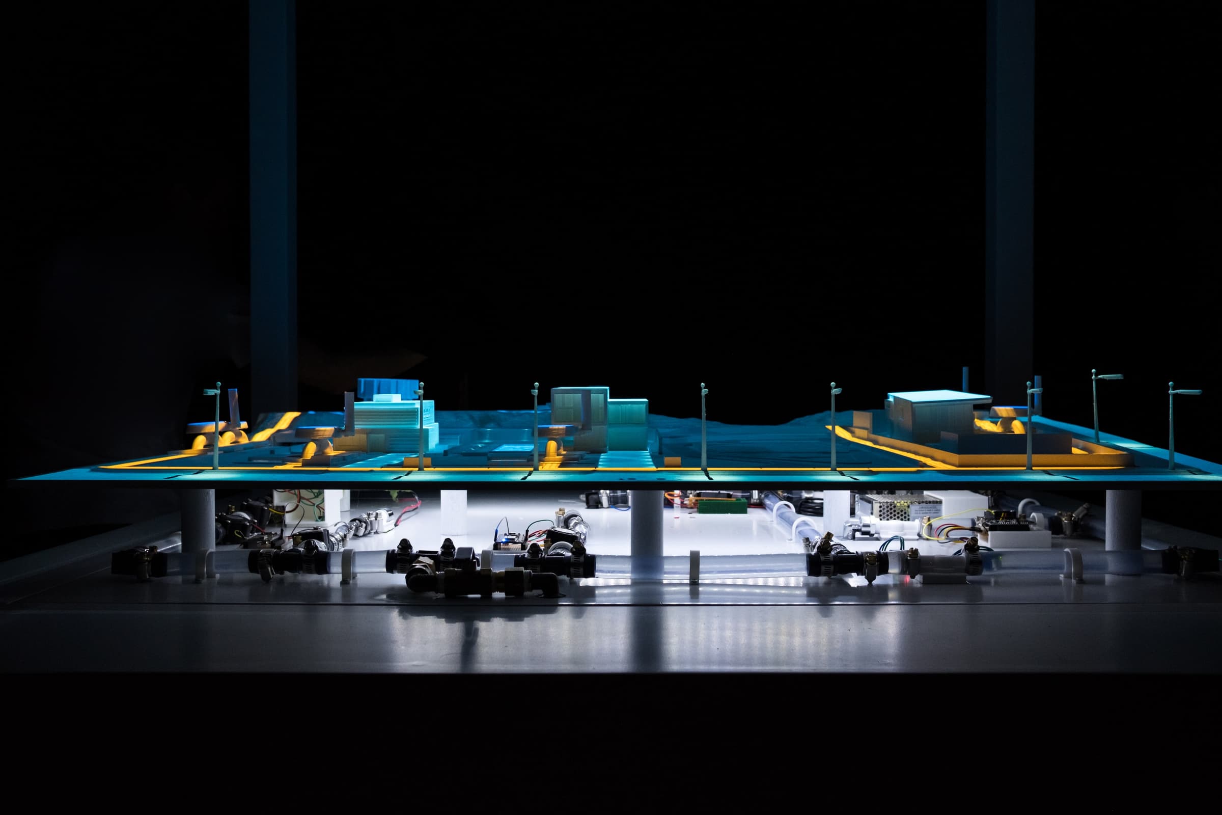 Front view of the finished H2.0 physical network, with the model above the visible water pipes, valves and connected components.